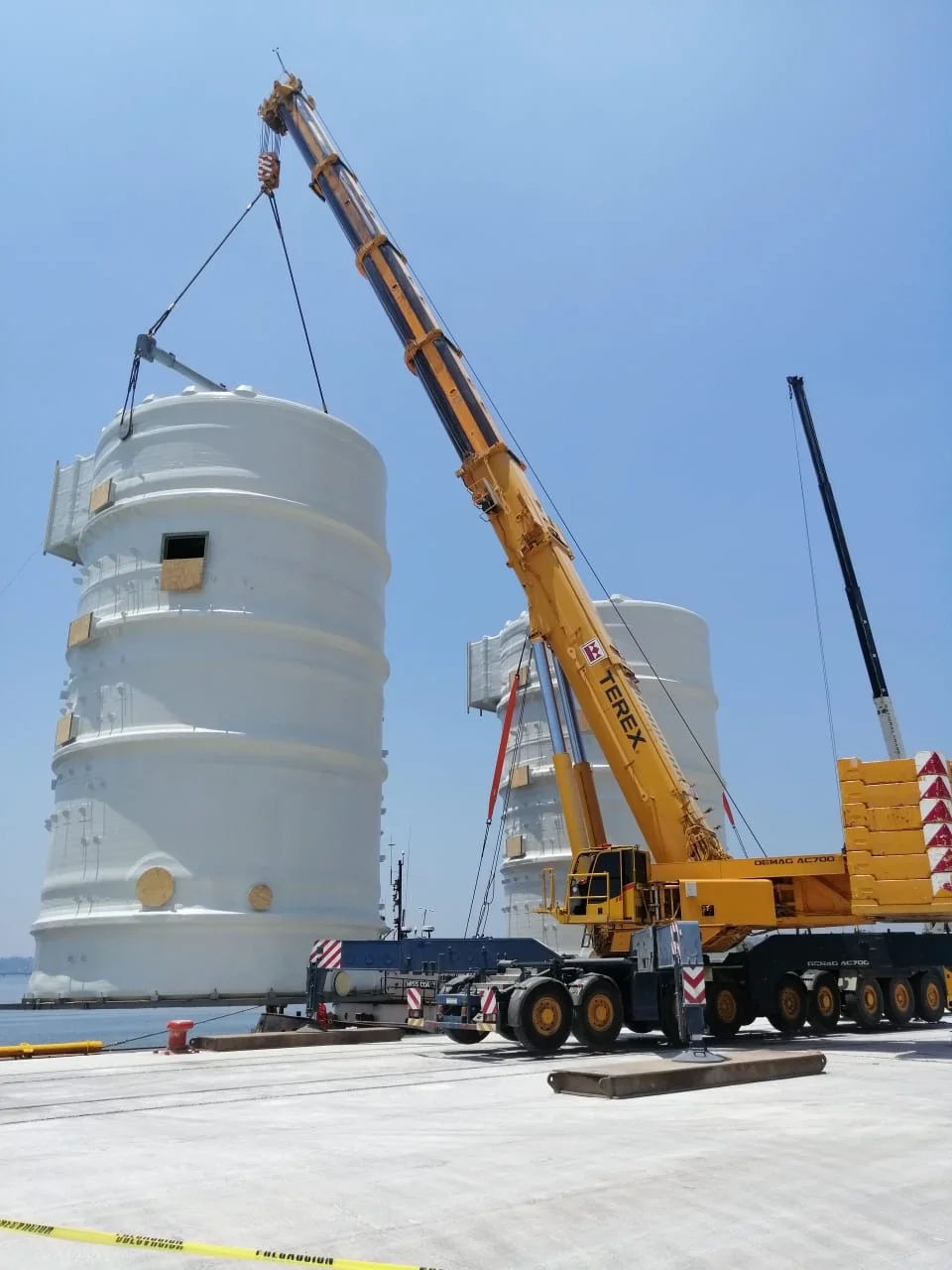 Grúas Equiser amarillas izando tanques blancos grandes en Petromonagas